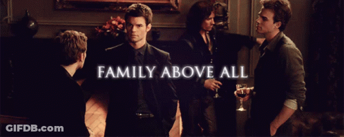 A Group Of Men Are Standing In A Room With The Words Family Above All GIF