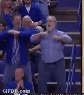 A Group Of Men Are Standing In A Stadium With Their Arms Outstretched During A Basketball Game . GIF
