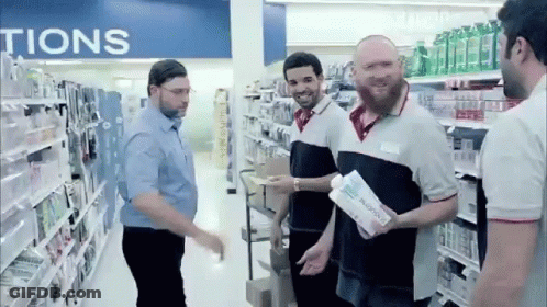 A Group Of Men Are Standing In A Store Aisle Under A Sign That Says ' Tions ' GIF