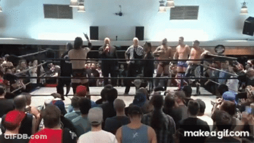 A Group Of Men Are Standing In A Wrestling Ring With A Crowd Watching GIF