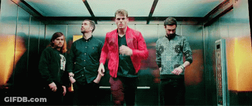 A Group Of Men Are Standing In An Elevator . One Of The Men Is Wearing A Red Jacket . GIF