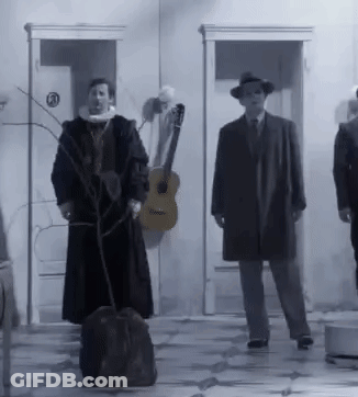 A Group Of Men Are Standing In Front Of A Building With A Guitar In The Background . GIF
