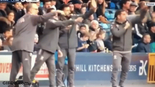 A Group Of Men Are Standing In Front Of A Hill Kitchens Sign GIF