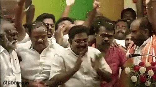 A Group Of Men Are Standing In Front Of A Microphone With Their Arms In The Air GIF