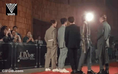 A Group Of Men Are Standing In Front Of A Podium That Says Uni5 GIF