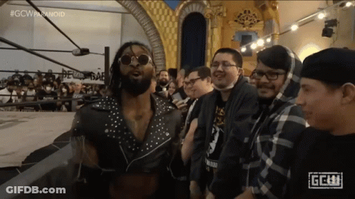 A Group Of Men Are Standing In Front Of A Sign That Says Gcw On It GIF