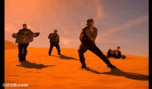 A Group Of Men Are Standing In The Middle Of A Desert . GIF
