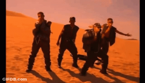 A Group Of Men Are Standing In The Sand In A Desert GIF