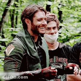 A Group Of Men Are Standing Next To Each Other In A Forest . GIF