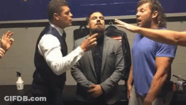 A Group Of Men Are Standing Next To Each Other In A Locker Room . One Of The Men Is Wearing A Suit . GIF