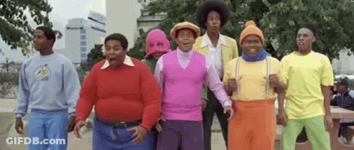 A Group Of Men Are Standing Next To Each Other In A Park Wearing Colorful Outfits . GIF