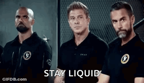 A Group Of Men Are Standing Next To Each Other In A Room With The Words `` Stay Liquid '' Written On The Screen . GIF