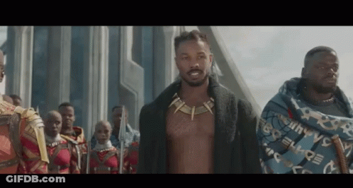 A Group Of Men Are Standing Next To Each Other In Front Of A Building . One Of The Men Is Without A Shirt On . GIF
