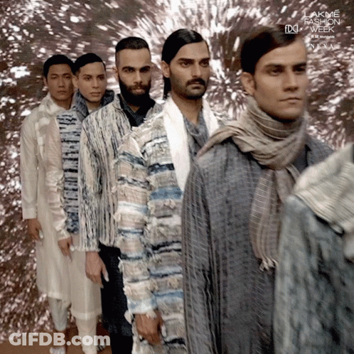 A Group Of Men Are Standing Next To Each Other In Front Of A Sign That Says Lakme Fashion Week Next GIF