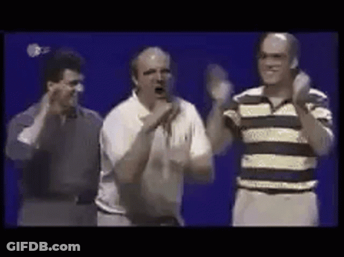 A Group Of Men Are Standing Next To Each Other On A Stage And Applauding . GIF