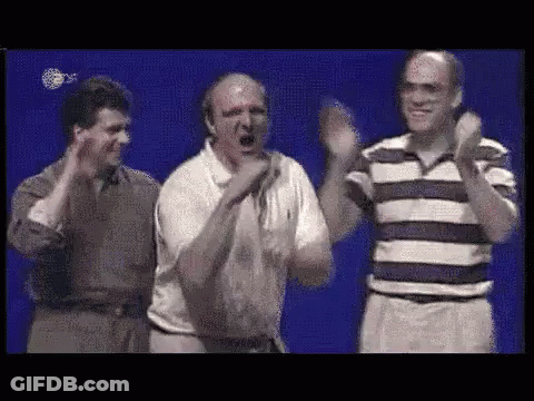 A Group Of Men Are Standing Next To Each Other On A Stage And Clapping Their Hands . GIF
