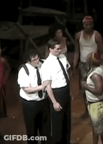A Group Of Men Are Standing Next To Each Other On A Stage In A Dark Room . GIF