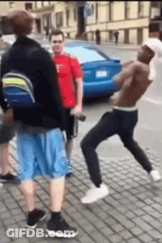 A Group Of Men Are Standing On A Brick Sidewalk Fighting Each Other . GIF