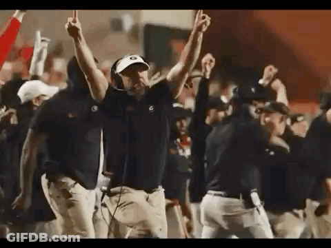 A Group Of Men Are Standing On A Football Field With Their Hands In The Air . GIF