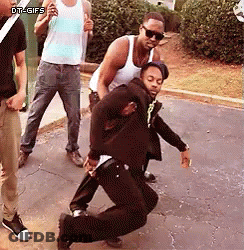 A Group Of Men Are Standing On A Sidewalk And One Of Them Is Dancing . GIF