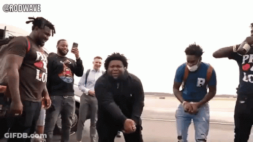 A Group Of Men Are Standing On A Street And One Of Them Is Wearing A Shirt That Says Rodwave GIF