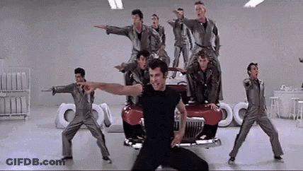 A Group Of Men Are Standing On Top Of A Red Car In A Garage . GIF