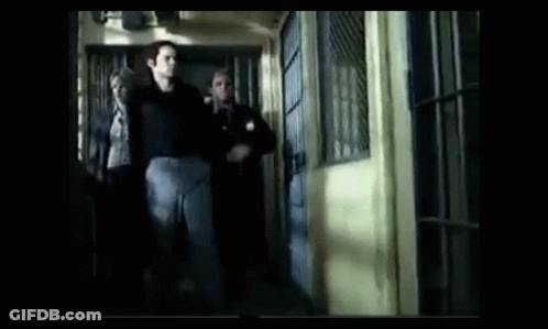 A Group Of Men Are Walking Down A Hallway In A Jail Cell GIF