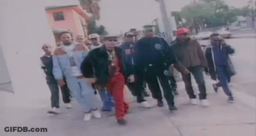 A Group Of Men Are Walking Down A Sidewalk In A Blurry Photo . GIF