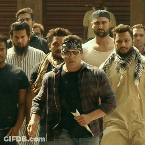 A Group Of Men Are Walking Down A Street And One Of Them Is Wearing Sunglasses GIF
