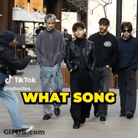 A Group Of Men Are Walking Down A Street With The Words What Song Behind Them GIF