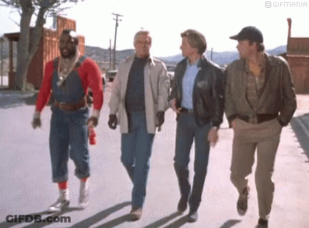 A Group Of Men Are Walking Down The Street . GIF