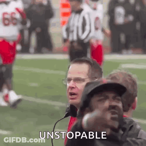 A Group Of Men Are Watching A Football Game And One Of Them Is Wearing A Hat And Glasses . GIF