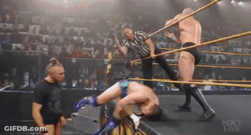 A Group Of Men Are Wrestling In A Ring While A Referee Looks On . GIF