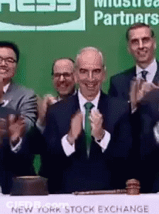 A Group Of Men Clapping In Front Of A New York Stock Exchange Table GIF