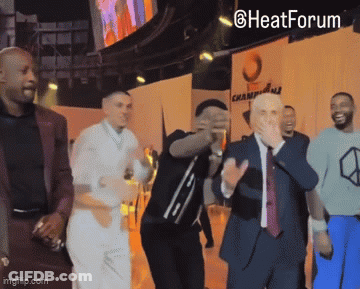 A Group Of Men Dancing In Front Of A Sign That Says Heat Forum GIF