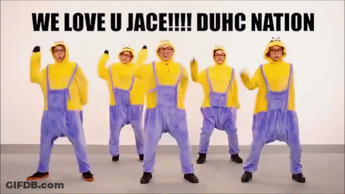 A Group Of Men Dressed As Minions Are Dancing In Front Of A Sign That Says We Love U Jace !!! Duhc Nation GIF