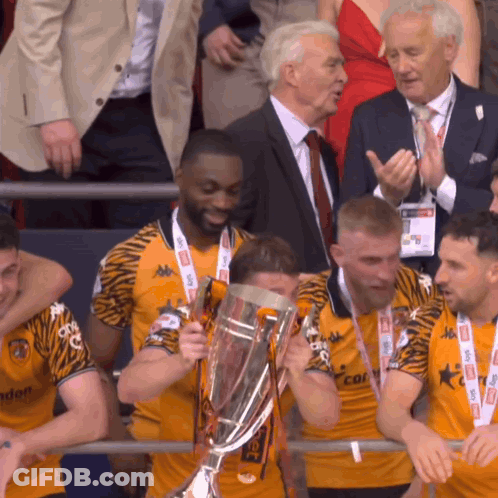 A Group Of Men Holding A Trophy With One Wearing A Shirt That Says ' Tigers ' On It GIF