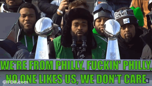 A Group Of Men Holding Trophies And A Sign That Says We 'Re From Philly Fuckin Philly No One Likes Us GIF