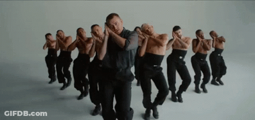 A Group Of Men In Black Pants Are Dancing In A Row . GIF