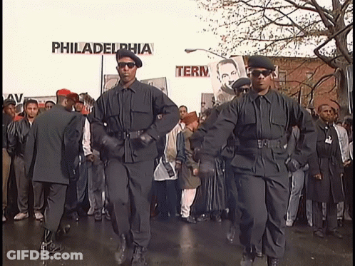 A Group Of Men In Black Uniforms Are Marching In Front Of A Sign That Says Philadelphia GIF