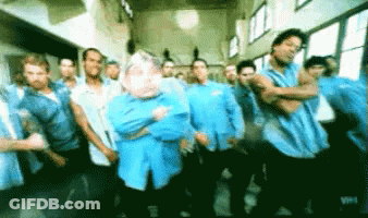 A Group Of Men In Blue Shirts Are Standing In A Hallway GIF