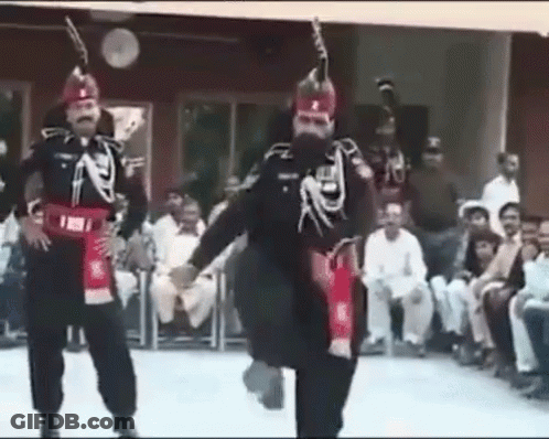 A Group Of Men In Military Uniforms Are Dancing In Front Of A Crowd Of People . GIF