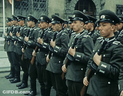 A Group Of Men In Military Uniforms Are Standing In A Line Holding Guns GIF