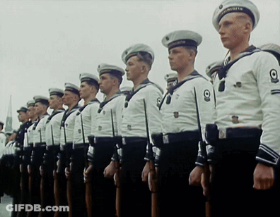 A Group Of Men In Military Uniforms Are Standing In A Row GIF