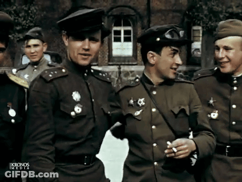 A Group Of Men In Military Uniforms Are Standing In Front Of A Building With Ikronos Media Written On The Bottom Right GIF