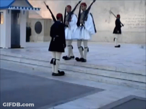 A Group Of Men In Military Uniforms Are Standing On A Sidewalk Holding Guns GIF