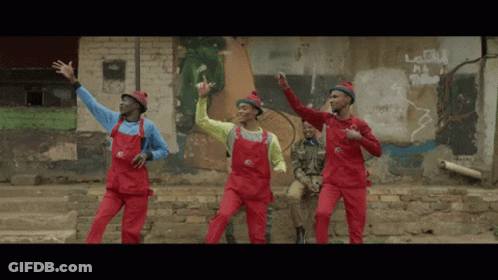 A Group Of Men In Red Overalls Are Dancing GIF