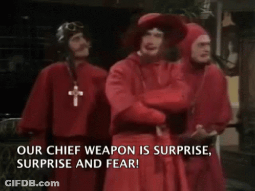 A Group Of Men In Red Robes Are Standing Next To Each Other With The Words " Our Chief Weapon Is Surprise Surprise And F GIF