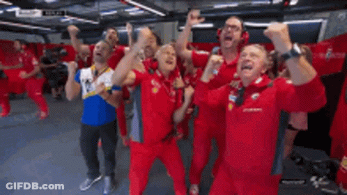 A Group Of Men In Red Uniforms Are Standing In A Room With Their Arms In The Air GIF