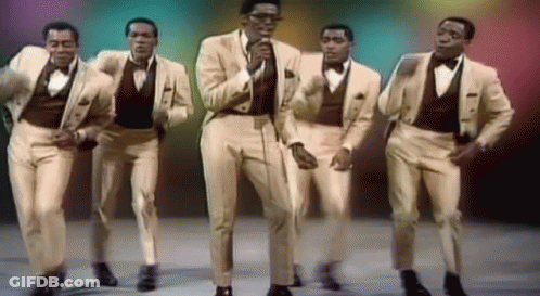 A Group Of Men In Suits And Bow Ties Are Dancing And Singing GIF